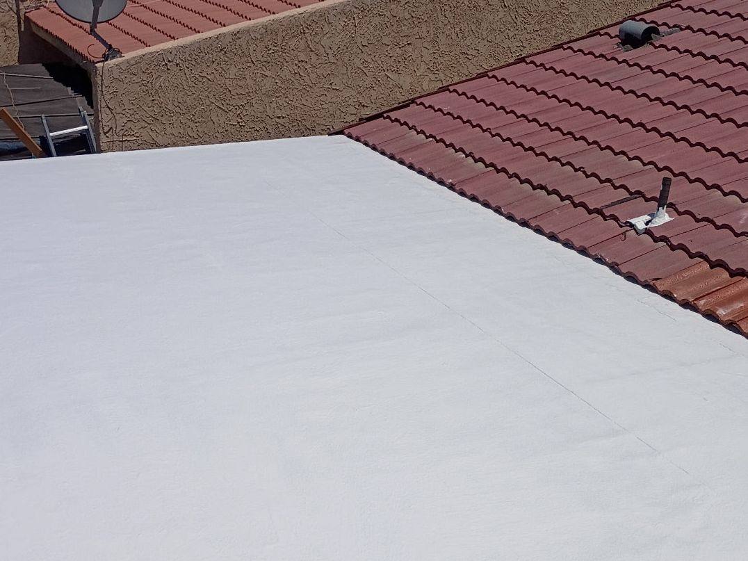 After: Flat section between tile roofs, Torn-up cap sheet and a failing tile edge, rebuilt, coated white and tied back into re-laid tile.
