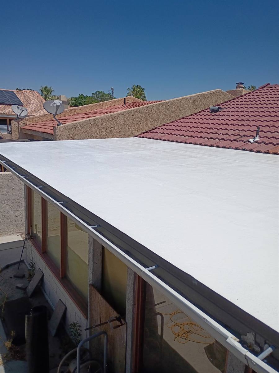 Finished white flat-roof coating next to a clay tile section