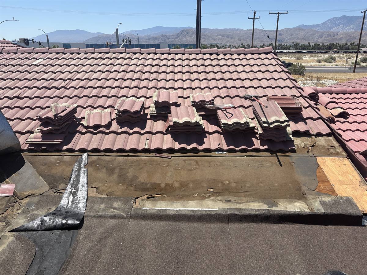 Storm-damaged tile roof showing failed underlayment beneath