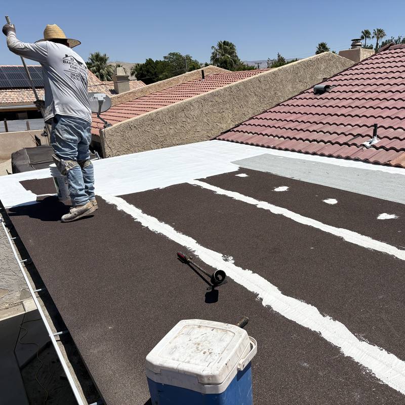 Sealing the cap sheet seams: Every seam on a new cap sheet sealed white, between two tile roofs.