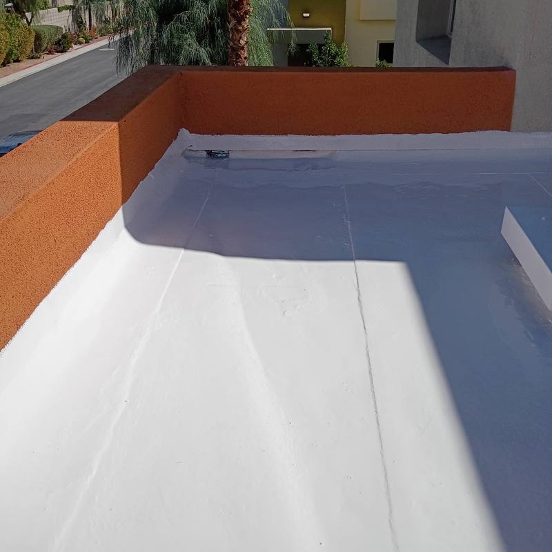 Parapet roof, finished: Smooth white coating run up to the edge of an orange stucco parapet.