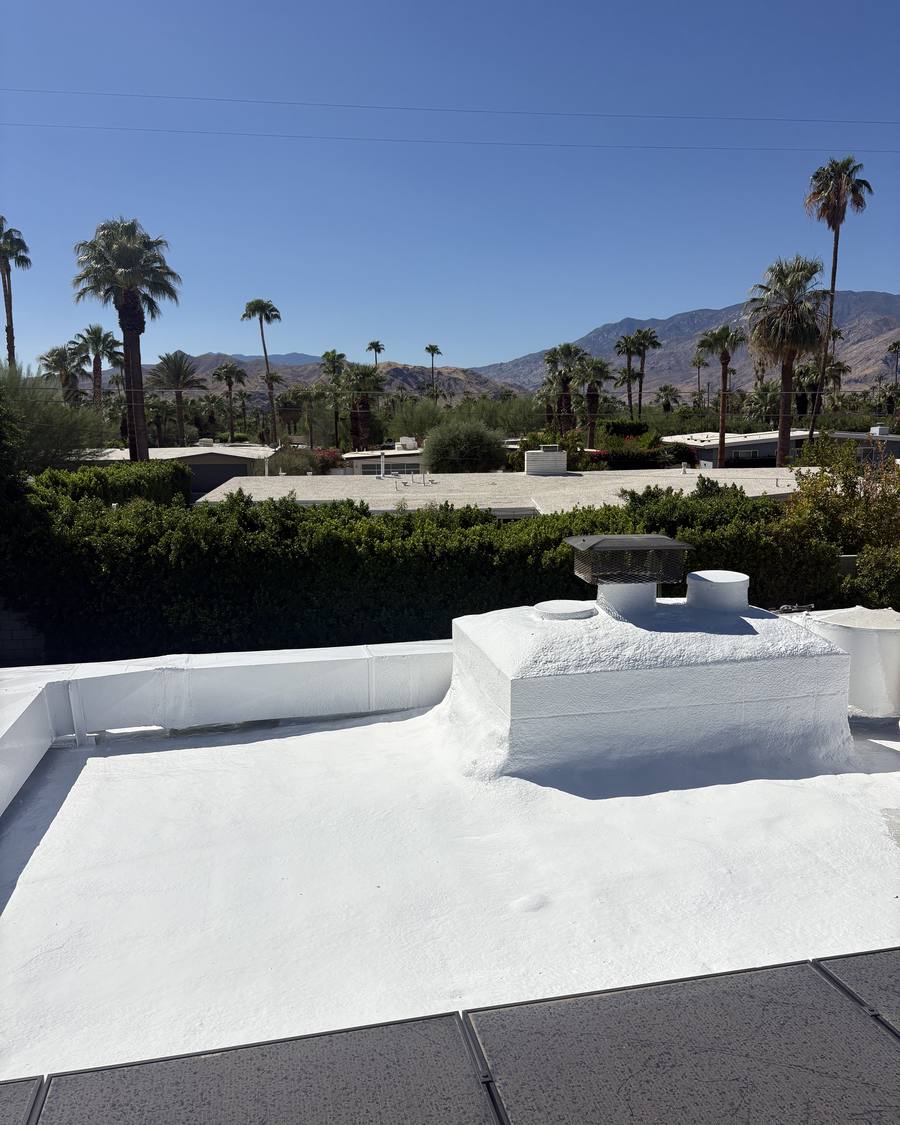 Coated parapet and chimney on a foam roof with mountain views