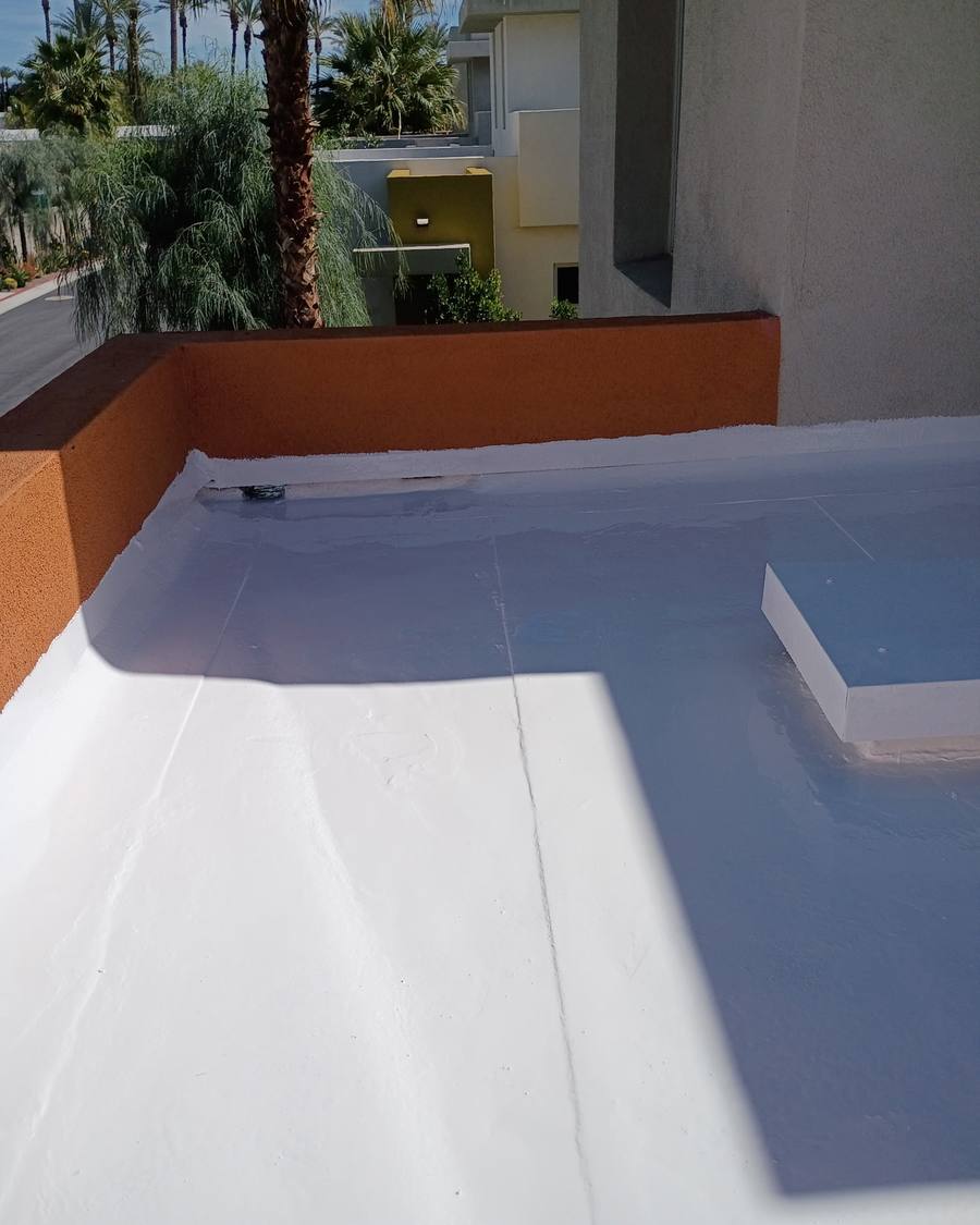 White coated flat roof beside an orange stucco parapet