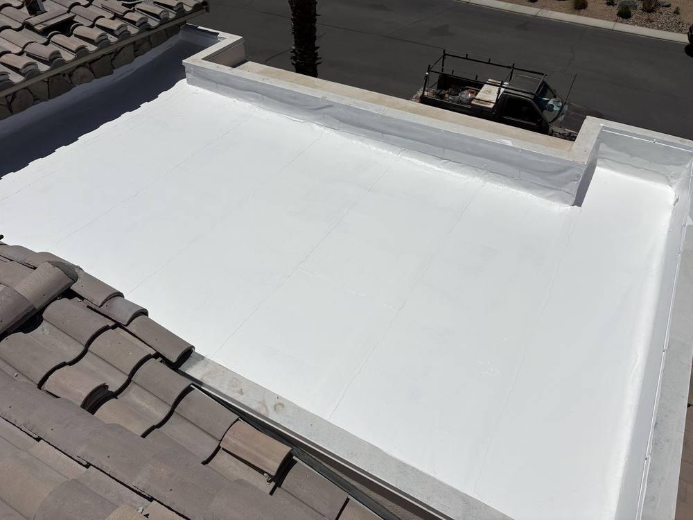 Bright white elastomeric coating on a parapet flat roof beside a tile roof
